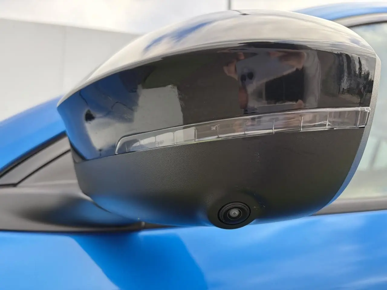 Gros plan sur le rétroviseur droit noir brillant avec caméra intégrée d’un Renault Rafale Summit Blue.
