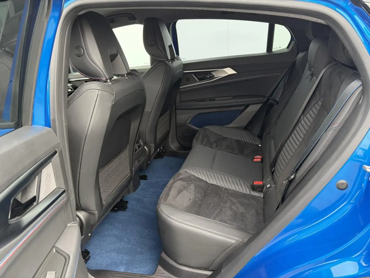 Vue côté gauche de l'intérieur arrière du Renault Rafale Summit Blue avec sellerie noire et tapis bleu.
