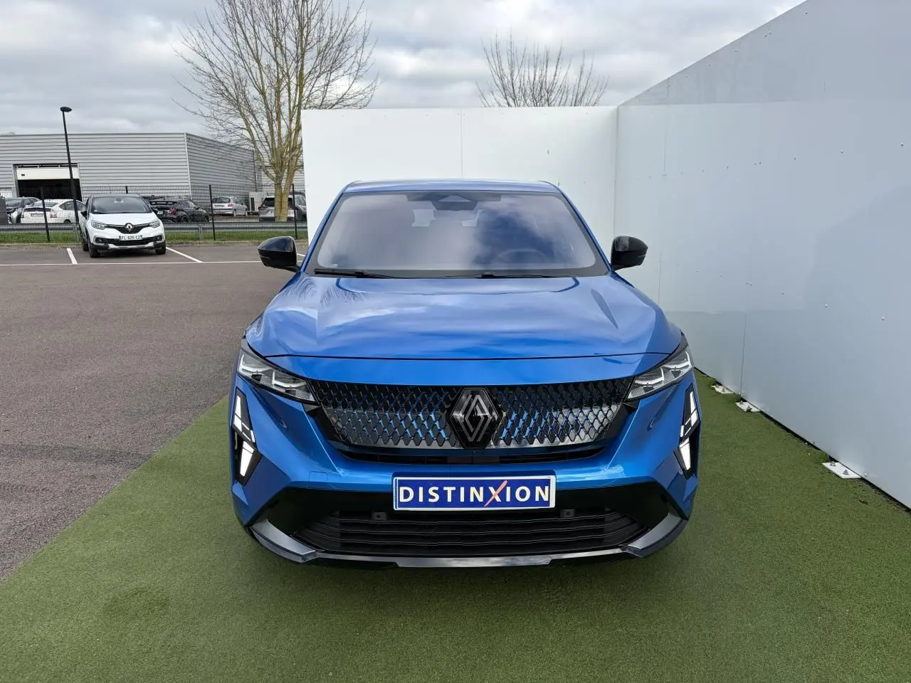 Vue frontale du Renault Rafale 1.2 E-TECH 4x4 en bleu Summit avec calandre noire et feux LED distinctifs.