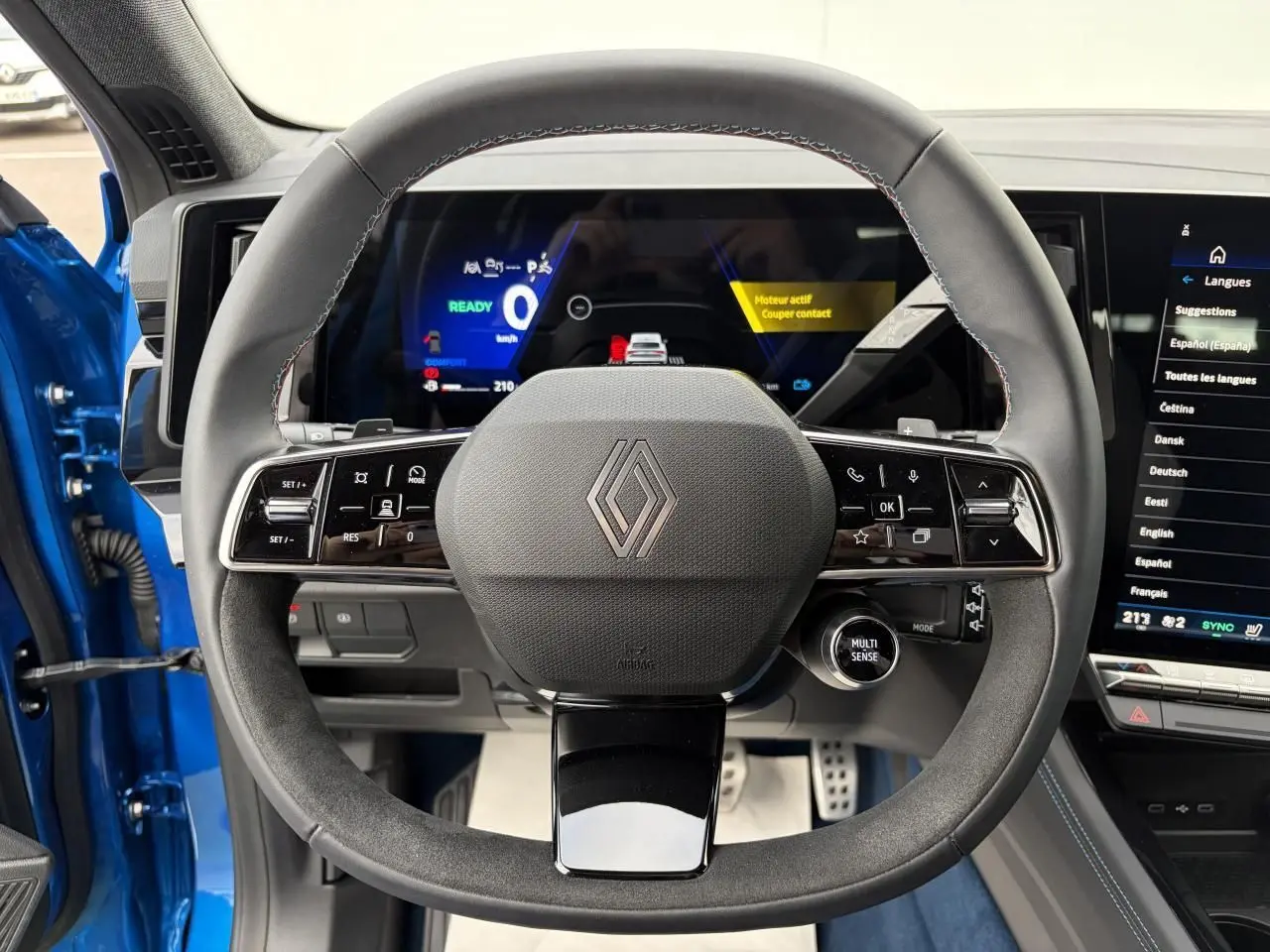 Vue centrée sur le volant Alcantara du Renault Rafale Summit Blue avec tableau de bord digital et écran tactile.