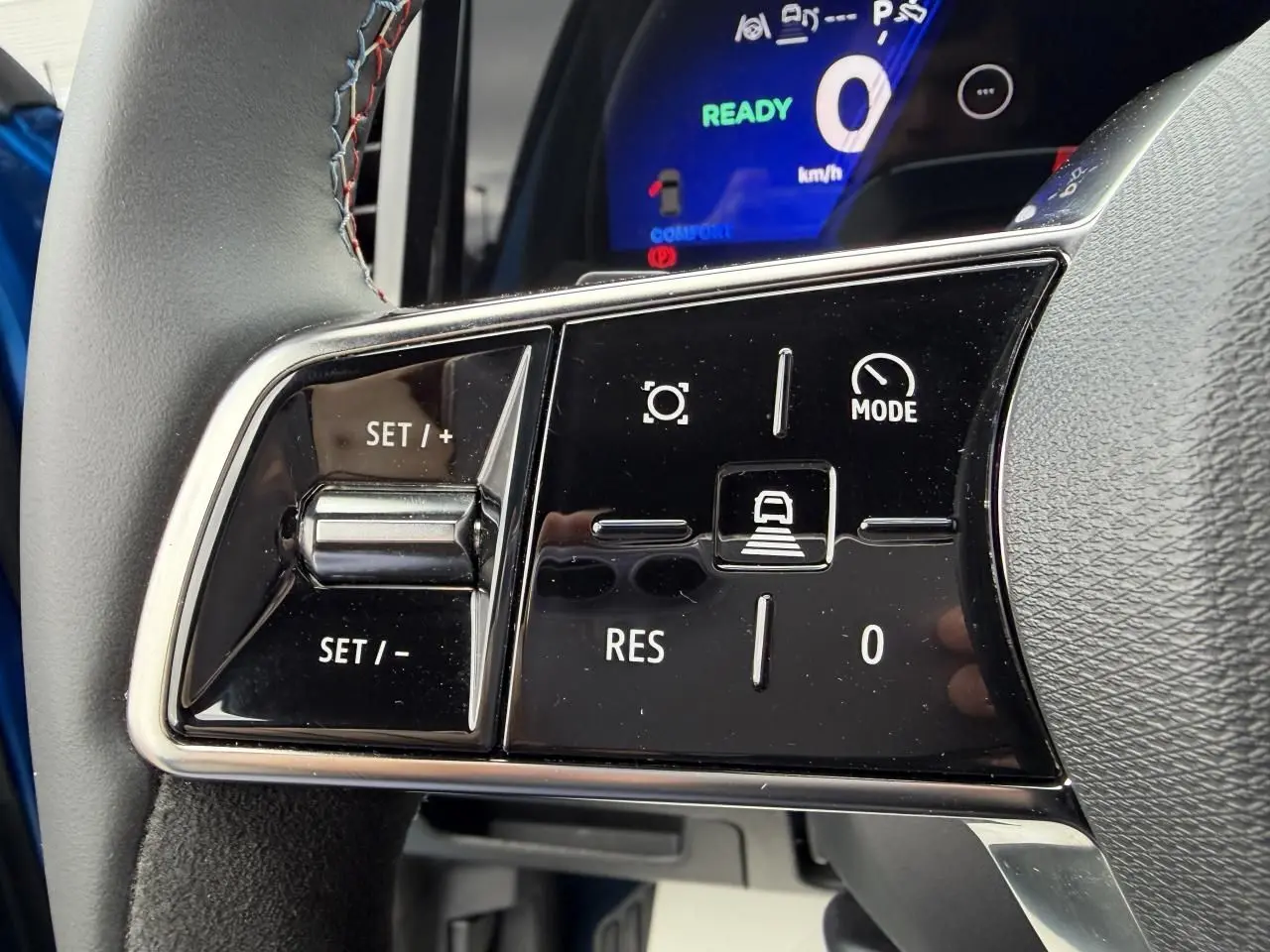 Gros plan sur les commandes au volant du Renault Rafale Summit Blue, affichage digital bleu en arrière-plan.