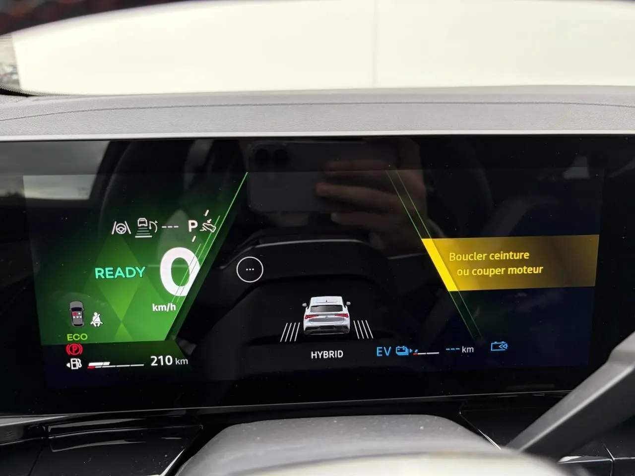 Écran numérique du tableau de bord montrant la Renault Rafale hybride en vue arrière stylisée avec alertes de sécurité affichées.