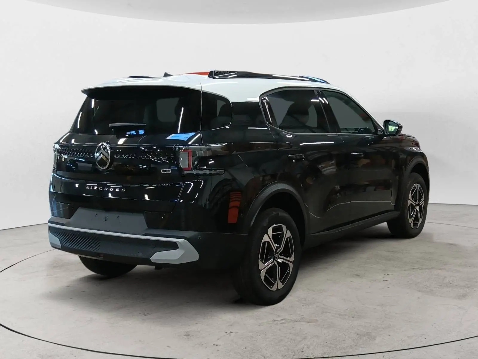 Vue 3/4 arrière droite du Citroën C3 Aircross 2025 noir Perla avec toit blanc, jantes bi-ton et feux LED distinctifs.