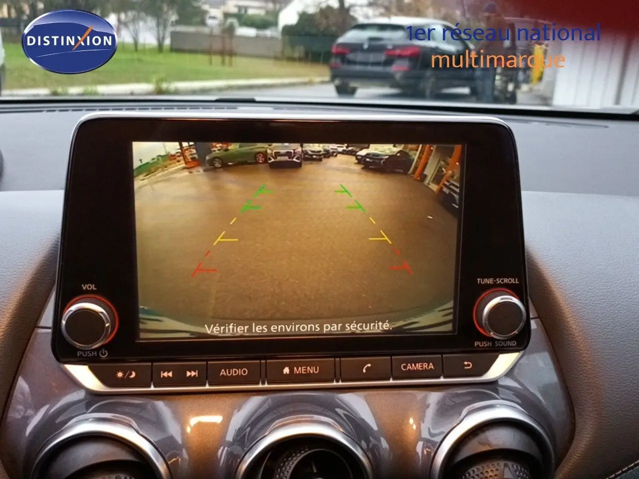 Écran central du Nissan Juke gris platine 2020 montrant la caméra de recul avec guidage coloré en intérieur.