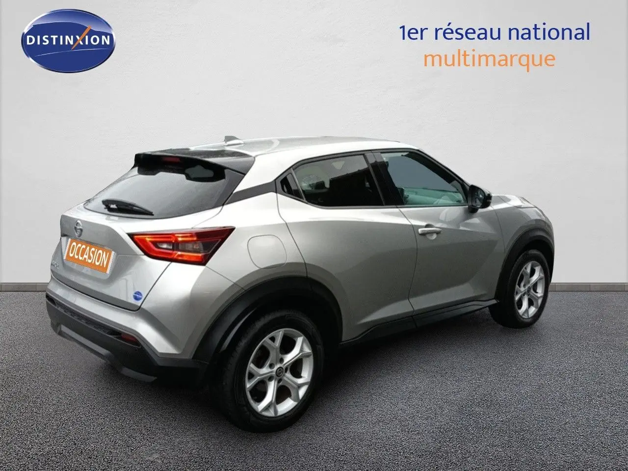 Vue 3/4 arrière droite d'un Nissan Juke gris platine métallisé avec jantes alliage et feux arrière allumés.