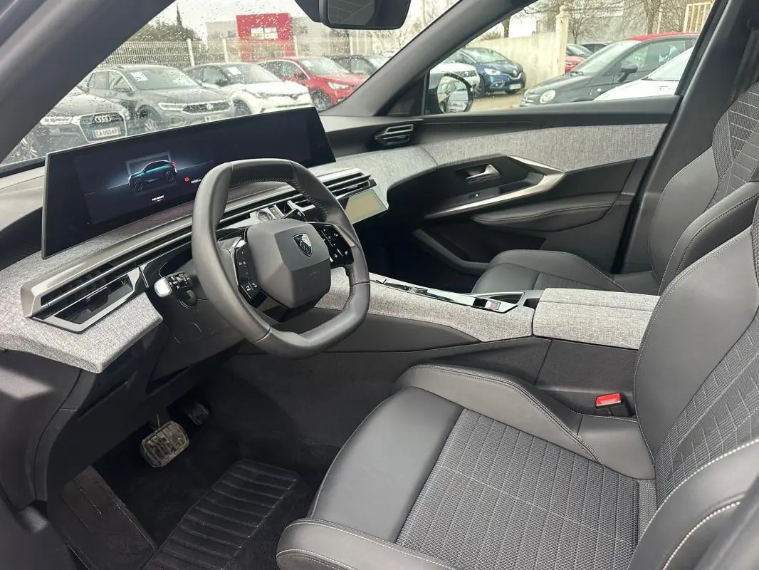 Vue intérieure côté conducteur du Peugeot 3008 Hybrid gris 2025, avec cockpit numérique et sellerie noire.