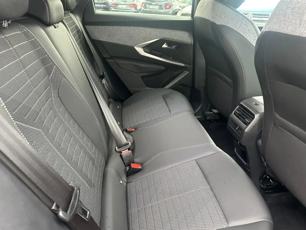 Vue intérieure côté droit des sièges arrière gris foncé du Peugeot 3008 Hybrid 136 e-DCS6 Allure 2025 avec ceintures de sécurité visibles.