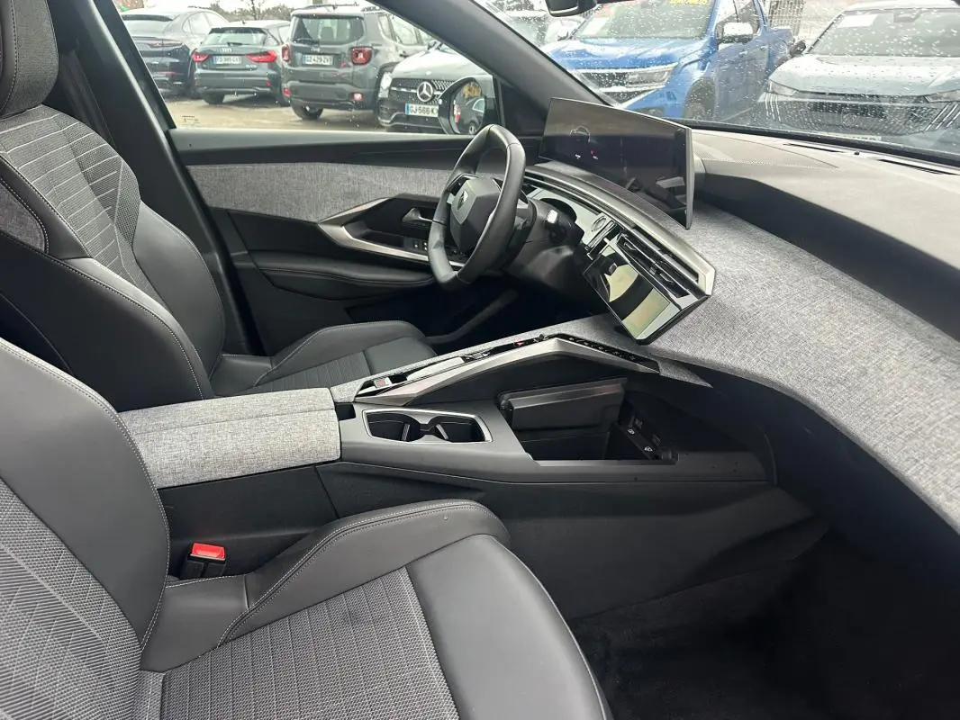 Vue intérieure côté conducteur du Peugeot 3008 Hybrid 136 gris 2025, avec tableau de bord moderne et sellerie mixte tissu-cuir.