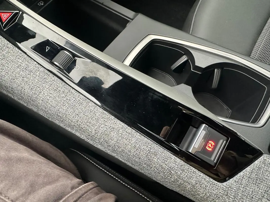 Vue rapprochée de la console centrale grise du Peugeot 3008 Hybrid 2025 avec frein de parking automatique lumineux.