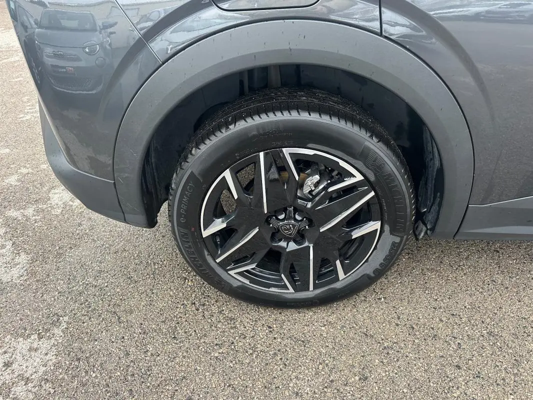 Gros plan sur la roue avant gauche du Peugeot 3008 Hybrid gris 2025 avec jante alliage noire et argent 19 pouces.