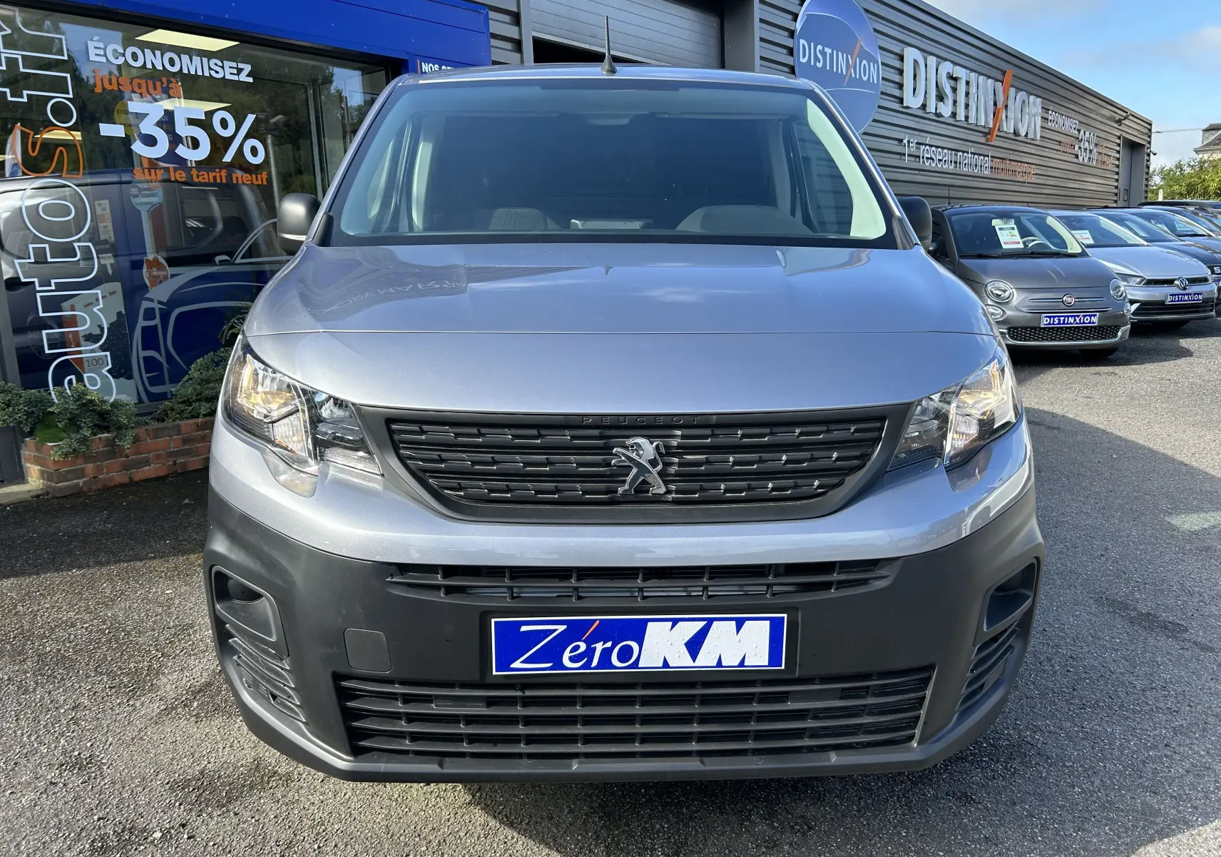 Vue avant d'un Peugeot Partner Dangel 4x4 gris Artense avec pare-chocs noir mat et plaque "Zéro KM" visible.