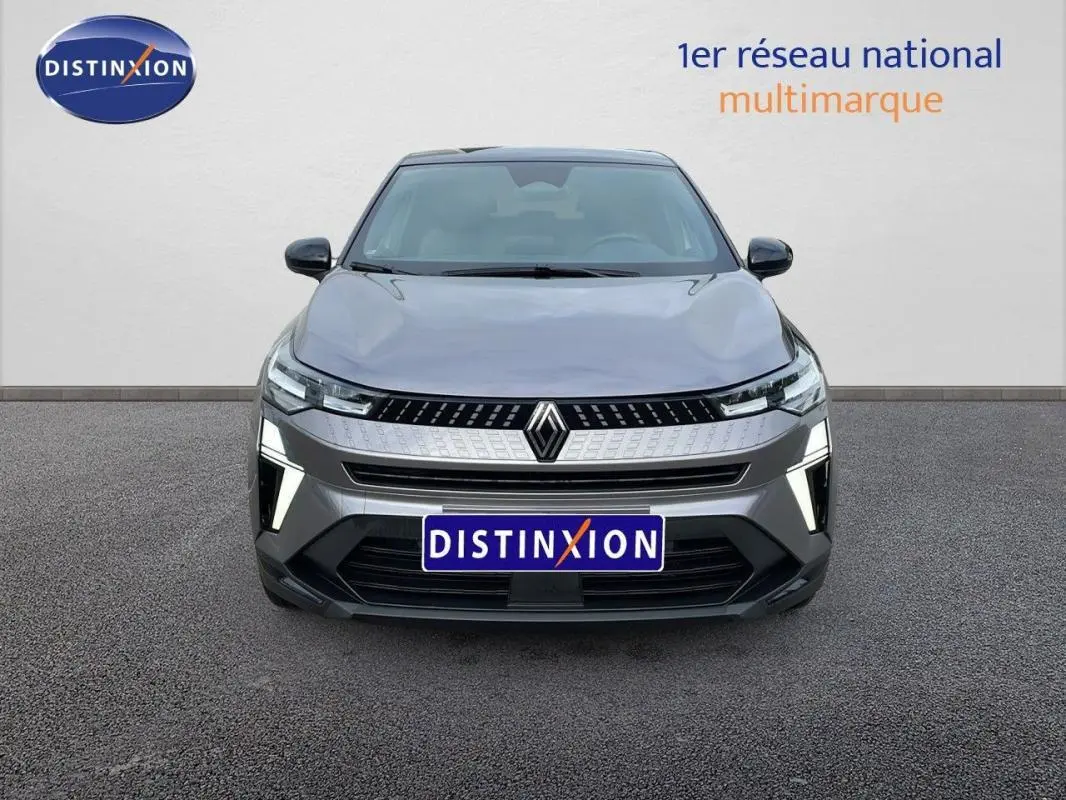 Vue frontale d'un Renault Captur gris 2025 avec calandre moderne et feux LED allumés sur fond neutre.