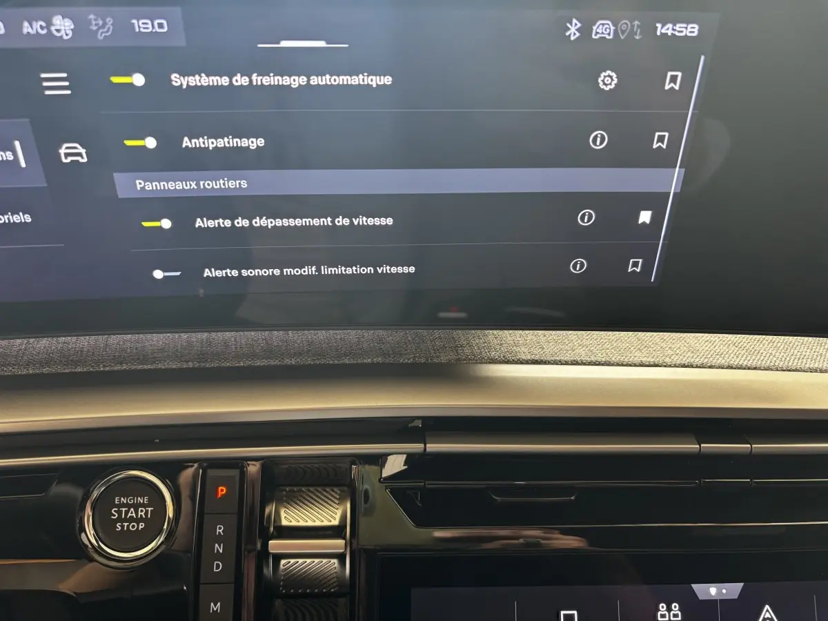 Détail intérieur du tableau de bord Peugeot 3008 gris clair avec bouton démarrage et écran tactile affichant les aides à la conduite.