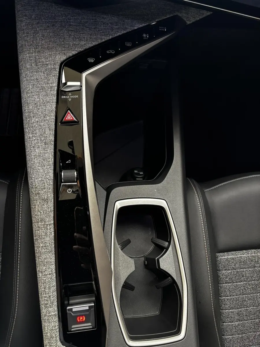 Vue rapprochée de la console centrale noire et grise du Peugeot 3008 1.2 Hybrid 145 Allure avec porte-gobelets et commandes tactiles.