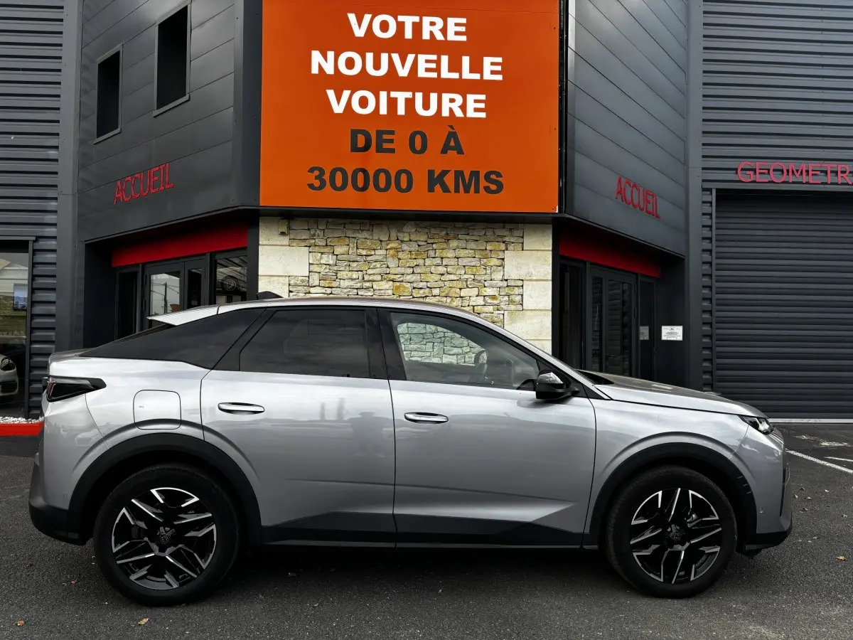 Peugeot 3008 hybride gris clair vue de profil côté gauche, roues noires à jantes stylisées, stationnée devant un bâtiment.