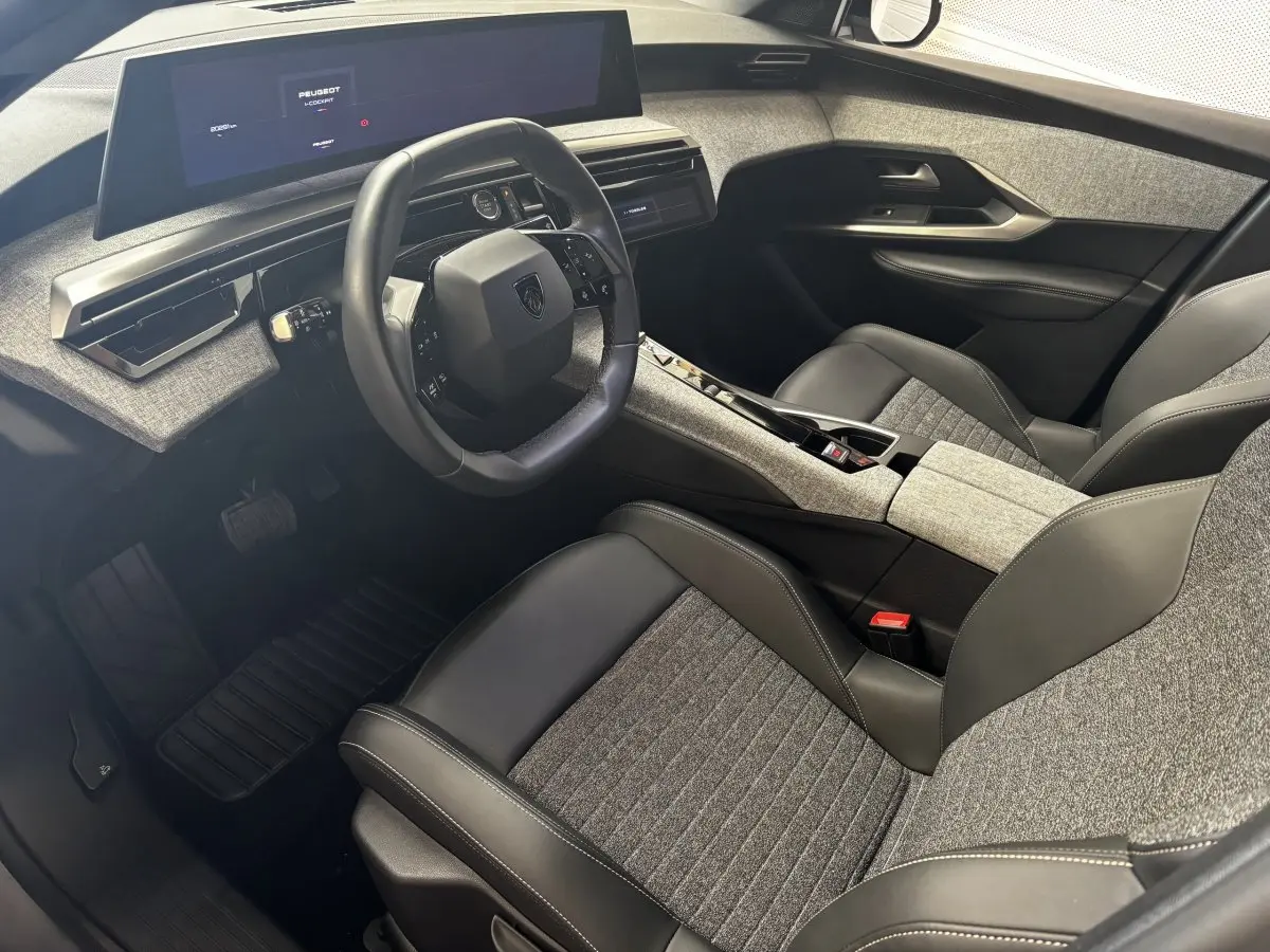 Vue intérieure côté conducteur du Peugeot 3008 2025 hybride, avec sièges bi-matière gris et noir et tableau de bord digital.