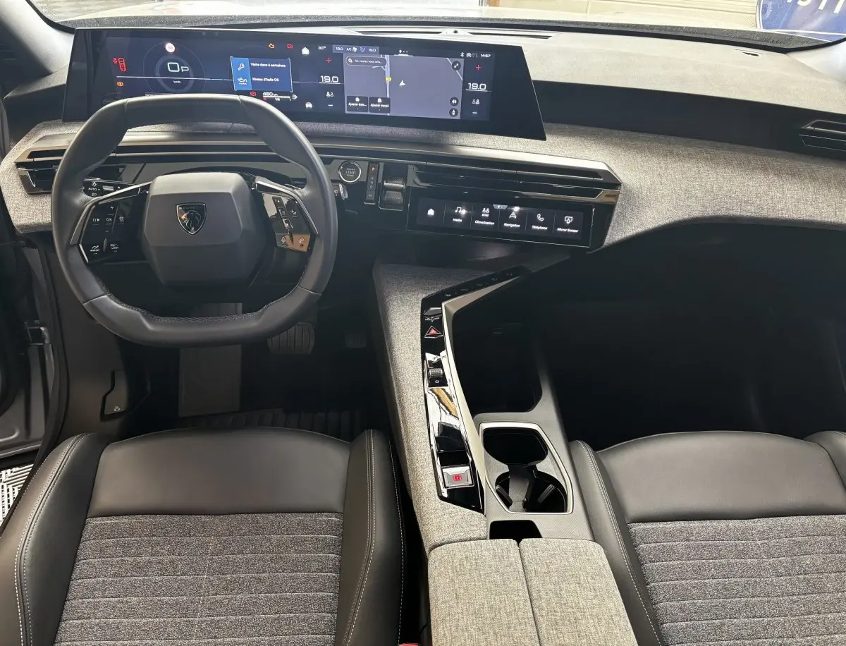 Vue intérieure avant du Peugeot 3008 1.2 Hybrid 145 Allure 2025, tableau de bord numérique et volant cuir multifonctions.