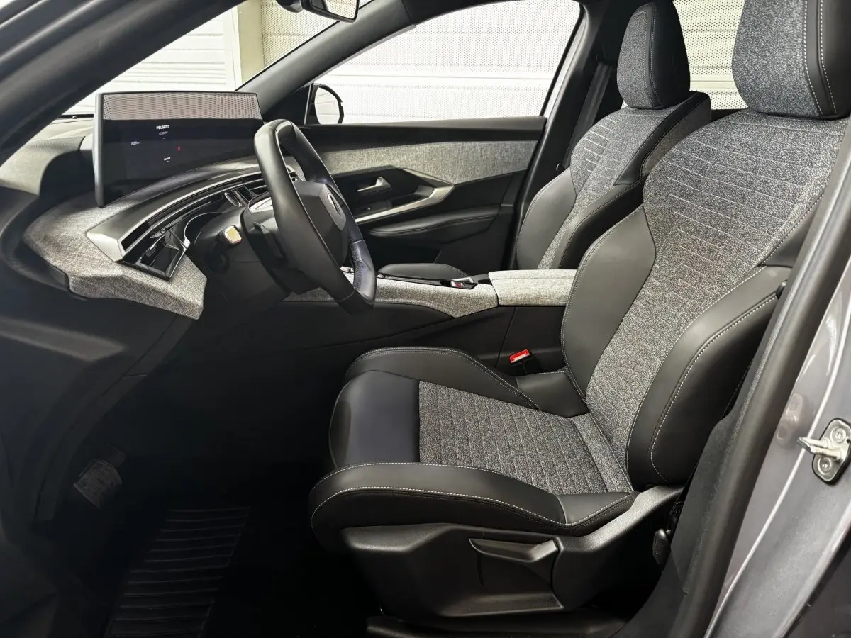 Vue intérieure côté conducteur du Peugeot 3008 gris clair 2025, sièges tissu et cuir, tableau de bord moderne avec écran tactile.