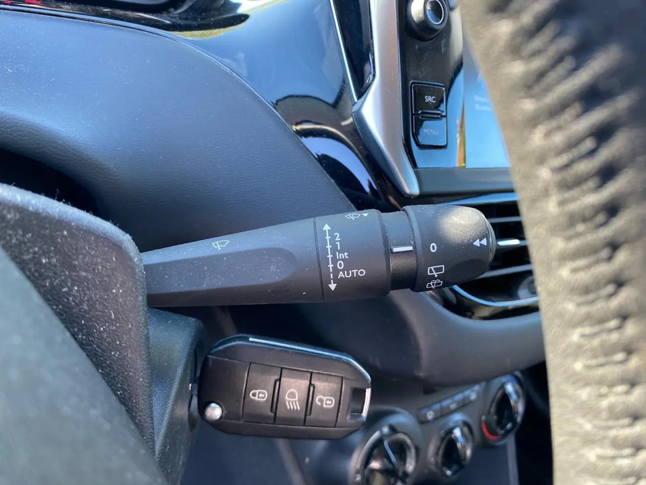 Gros plan sur la commande d’essuie-glace et la clé de contact dans l’habitacle d’une Peugeot 208 blanche de 2019.