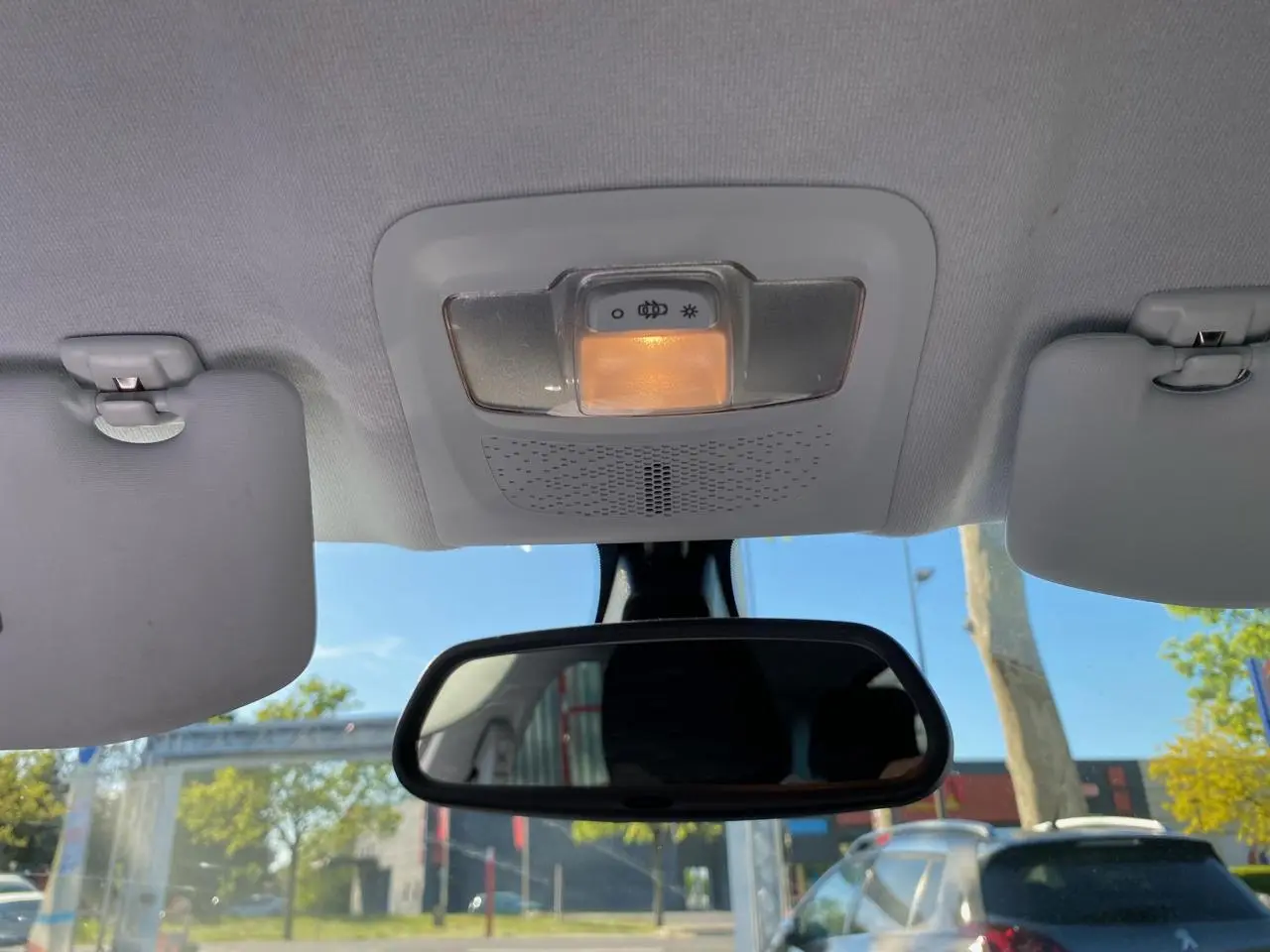 Vue intérieure centrée sur le plafonnier et le rétroviseur intérieur d’une Peugeot 208 blanche, avec pare-soleil baissé.