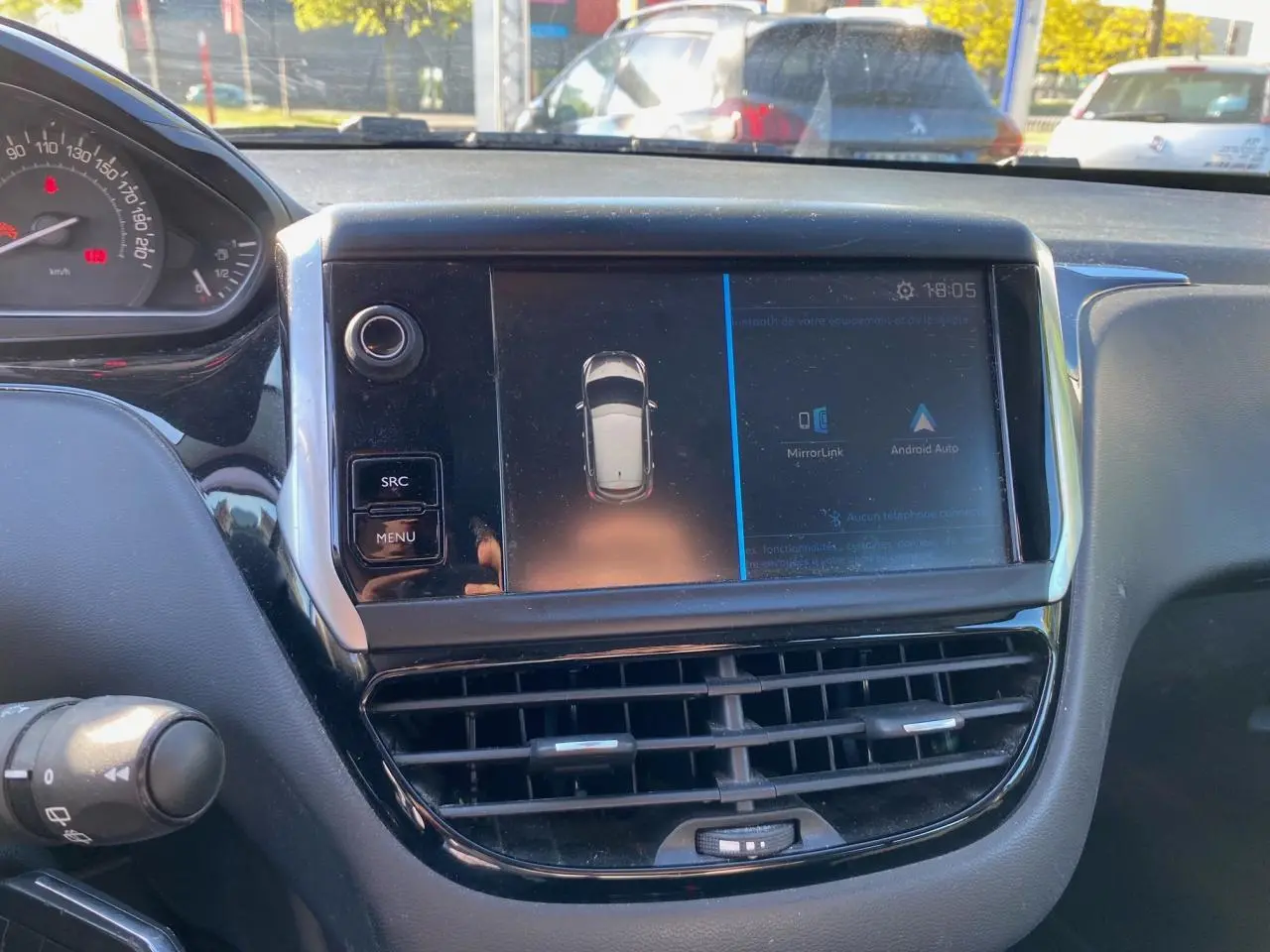 Vue rapprochée du tableau de bord de la Peugeot 208 blanche de 2019, avec écran tactile et commandes visibles.