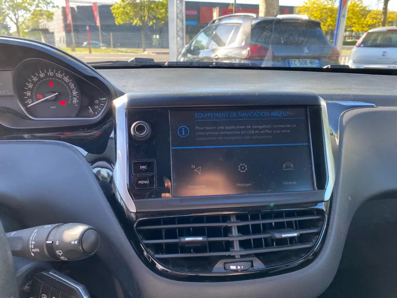 Vue intérieure du tableau de bord de la Peugeot 208 blanche de 2019, avec écran tactile et combiné de vitesse visible.