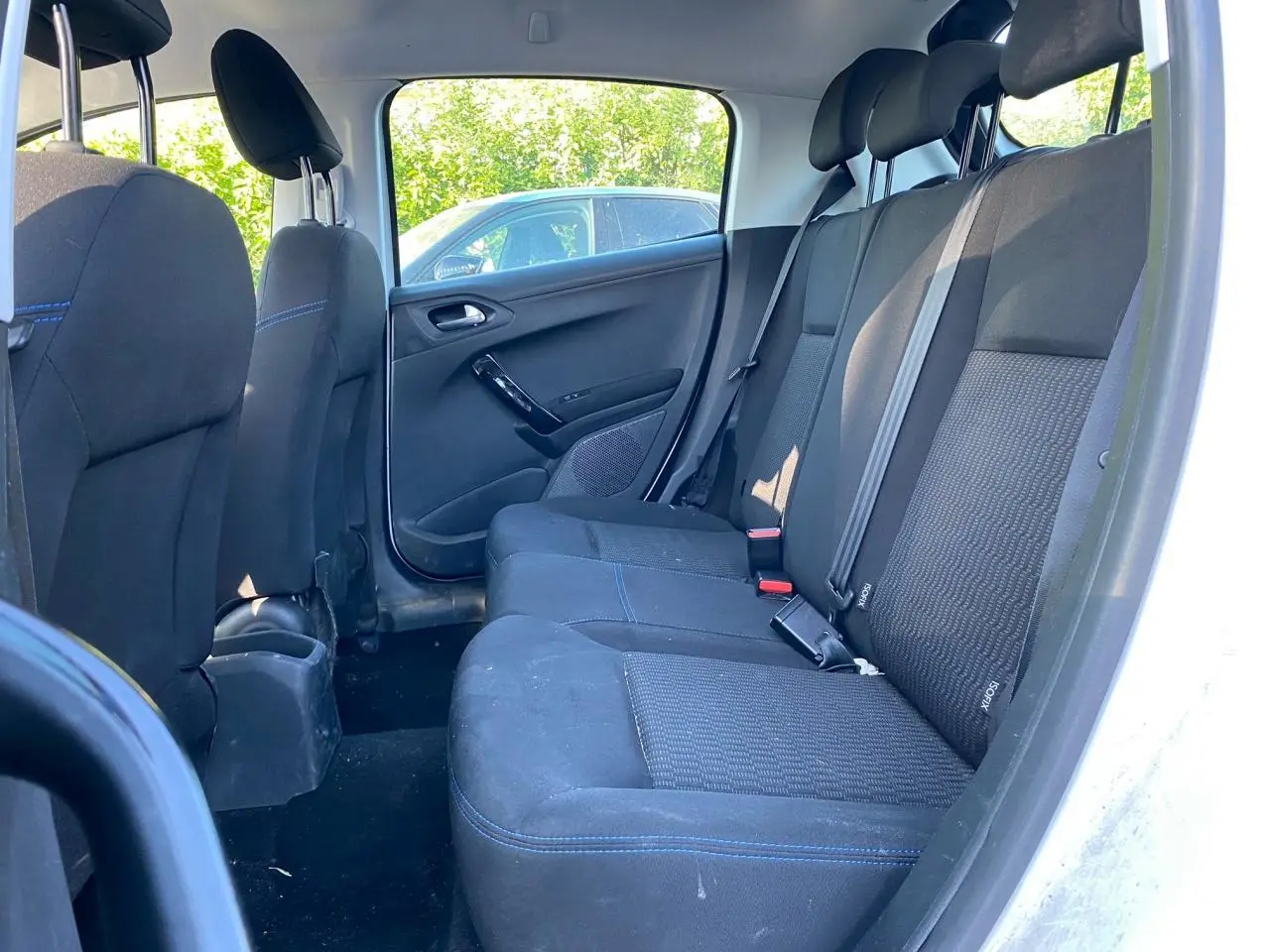 Vue intérieure arrière côté droit des sièges noirs avec surpiqûres bleues d'une Peugeot 208 blanche de 2019.