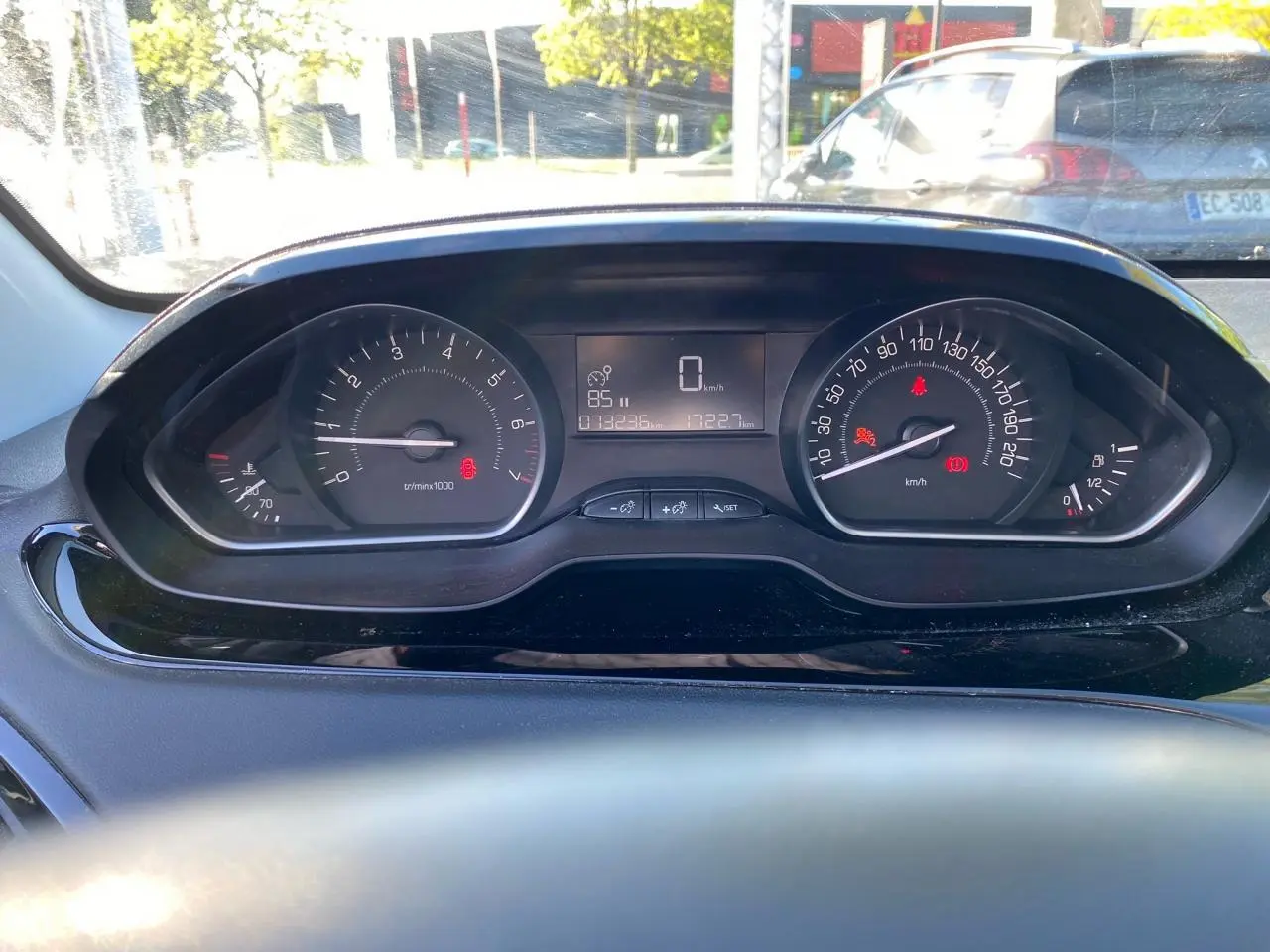 Vue rapprochée du combiné d'instruments numérique de la Peugeot 208 blanche, affichant la vitesse à 0 km/h.