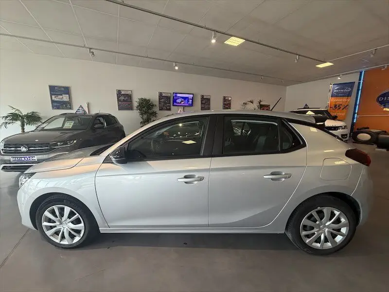 Vue de profil côté gauche d'une Opel Corsa gris clair 2025 en version 1.2 Turbo 100 Edition avec jantes alliage en showroom.