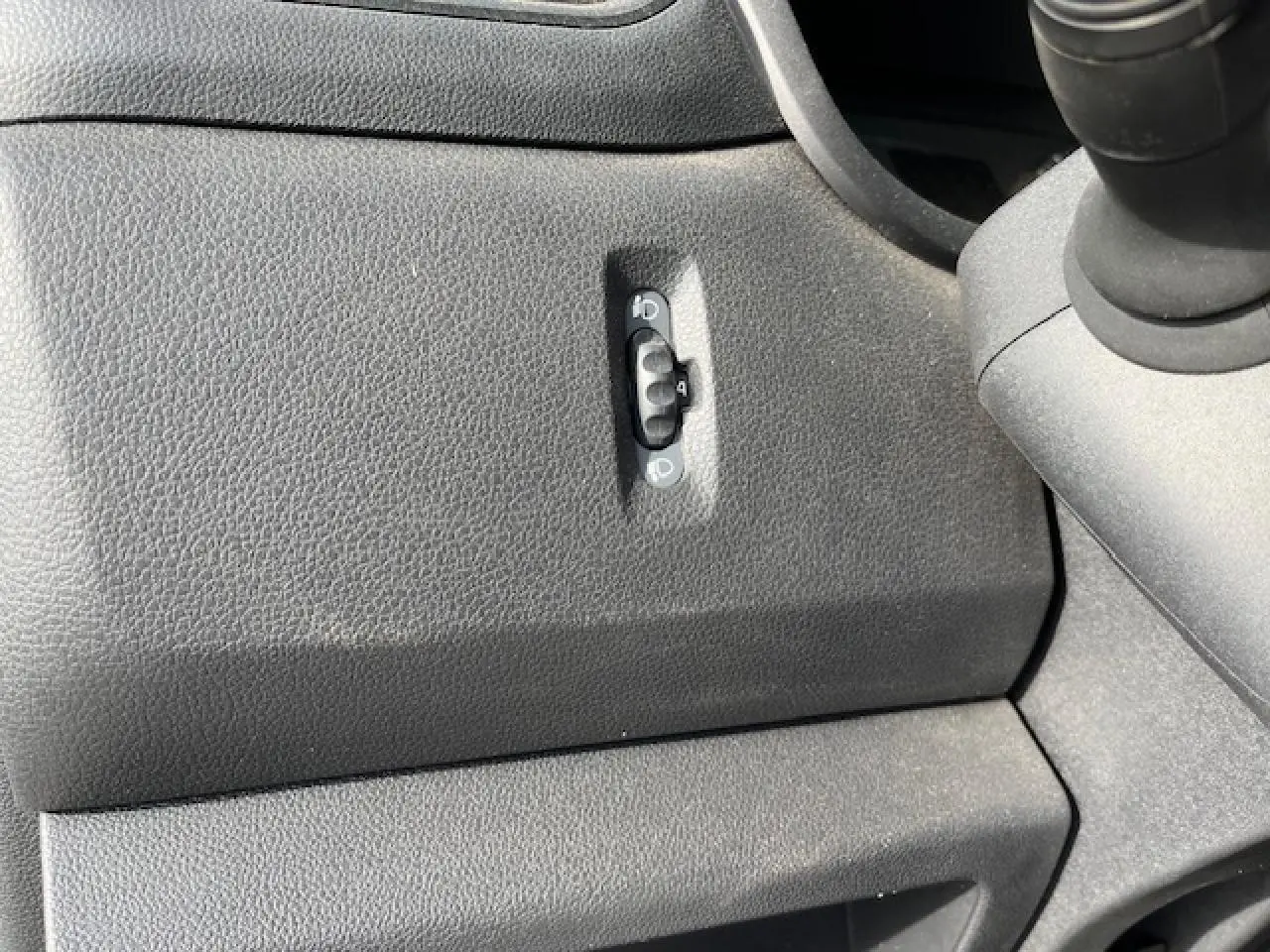 Gros plan sur le réglage des phares dans l’habitacle noir du Renault Master 2.3 dCi 130 Benne Basculante 2024.