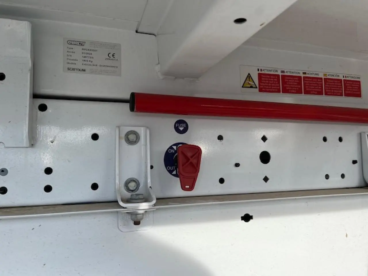 Détail du mécanisme de la benne basculante blanche Renault Master 2.3 dCi 130, vue rapprochée du levier rouge et cadre métallique.