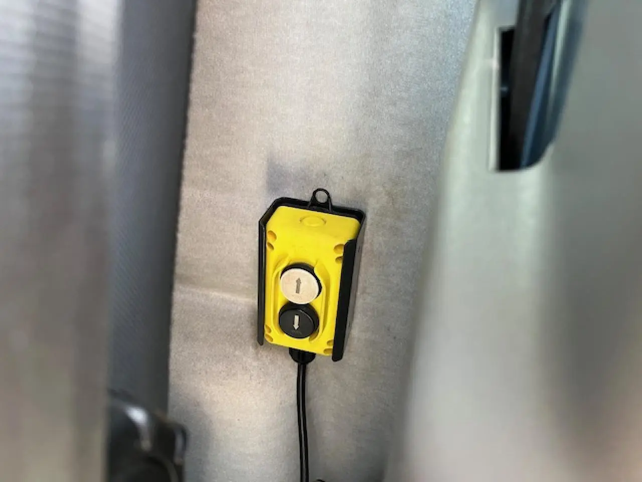 Vue intérieure rapprochée d’un bouton de commande jaune pour la benne basculante du Renault Master blanc 2024.