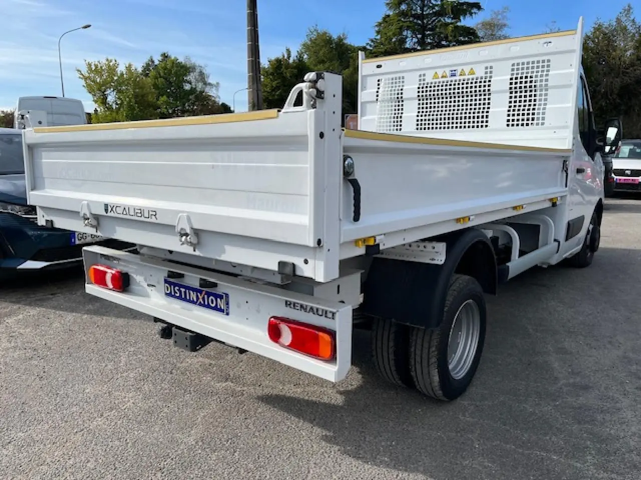 Vue 3/4 arrière droite d’un Renault Master blanc 2024 avec benne basculante et plaque d’immatriculation Distinxion.