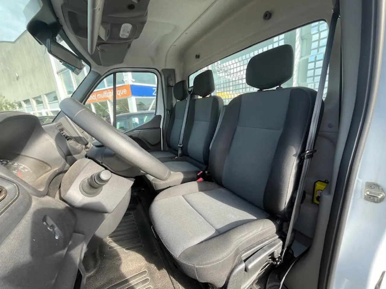 Intérieur du Renault Master 2024 vu côté conducteur, montrant les sièges gris et le volant à gauche.