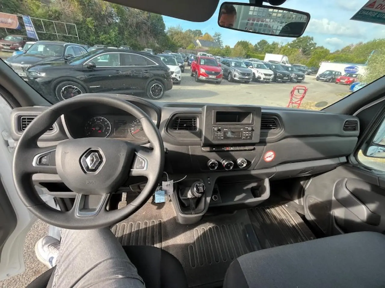 Vue intérieure du poste de conduite du Renault Master blanc 2024, avec volant, tableau de bord et levier de vitesses manuel visibles.