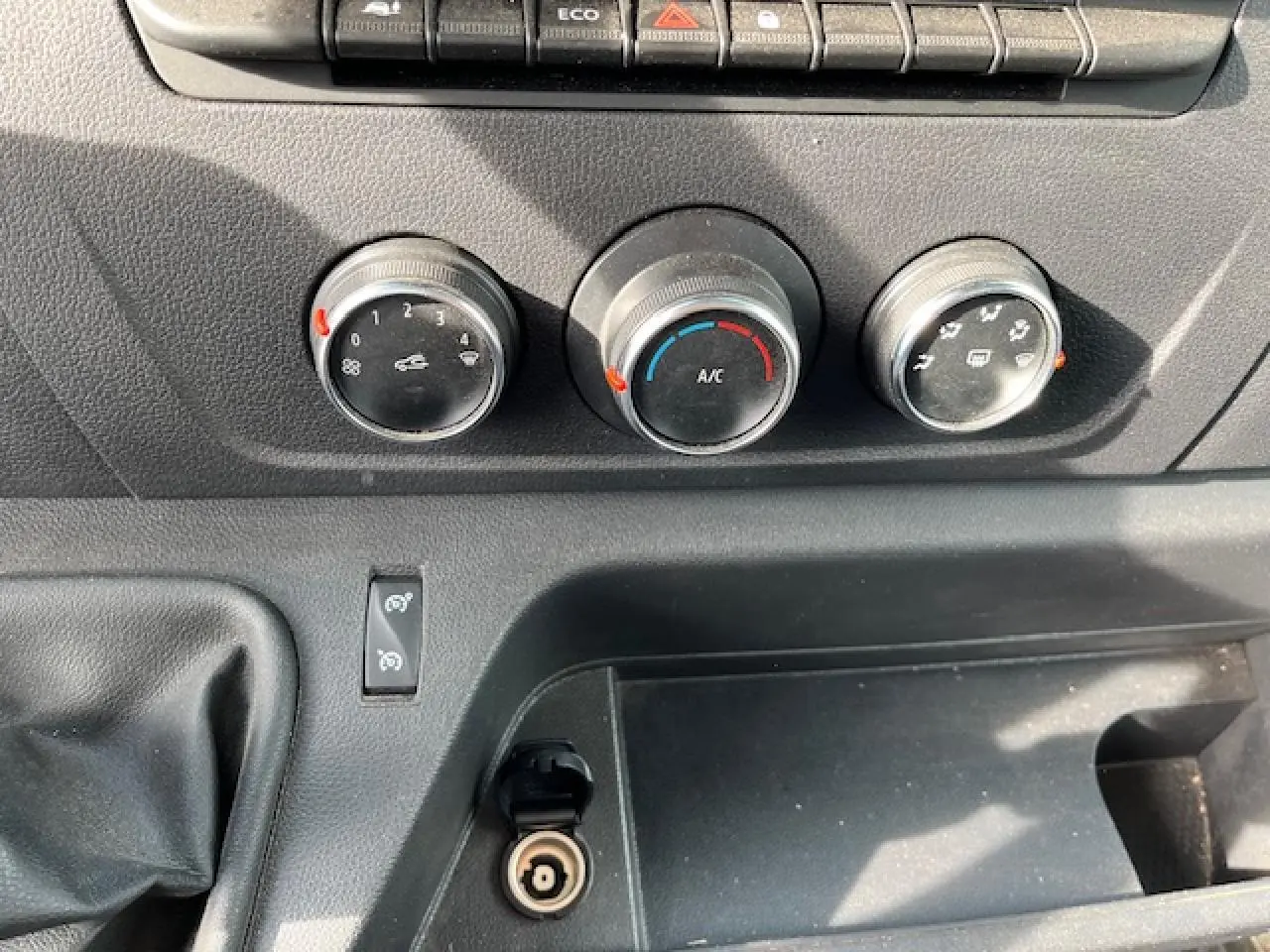 Détail du tableau de bord du Renault Master 2024 blanc, montrant les commandes de climatisation et la prise 12V.