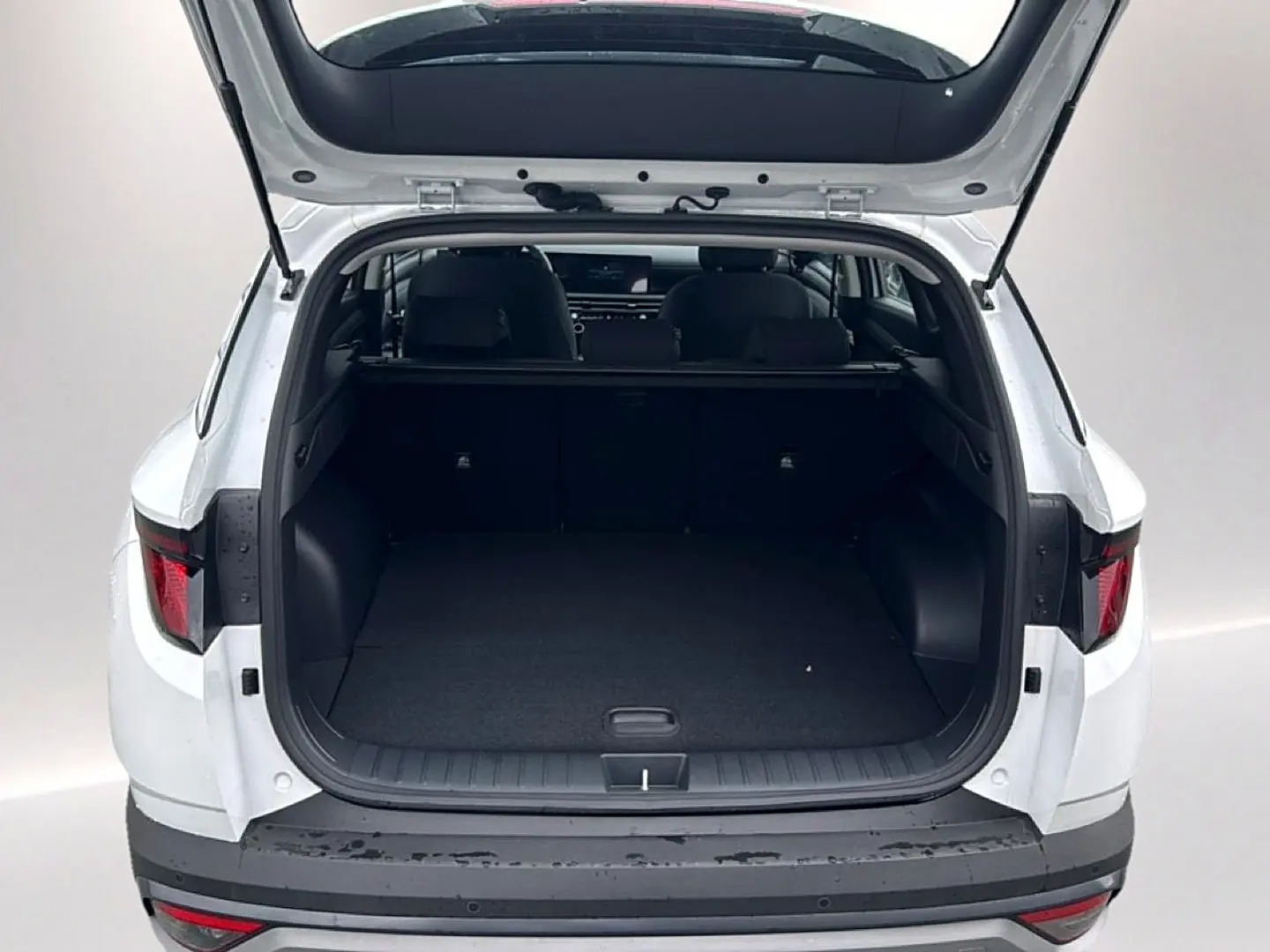 Vue arrière ouverte du Hyundai Tucson blanc 2026, mettant en valeur le coffre spacieux et l'intérieur sombre.