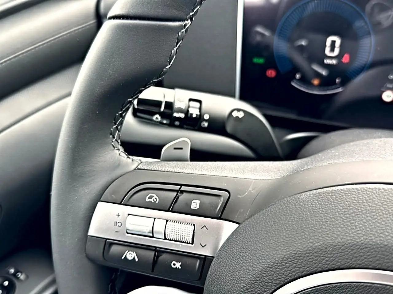 Gros plan sur le volant cuir multifonction du Hyundai Tucson 2026, avec commandes intégrées et tableau de bord numérique.