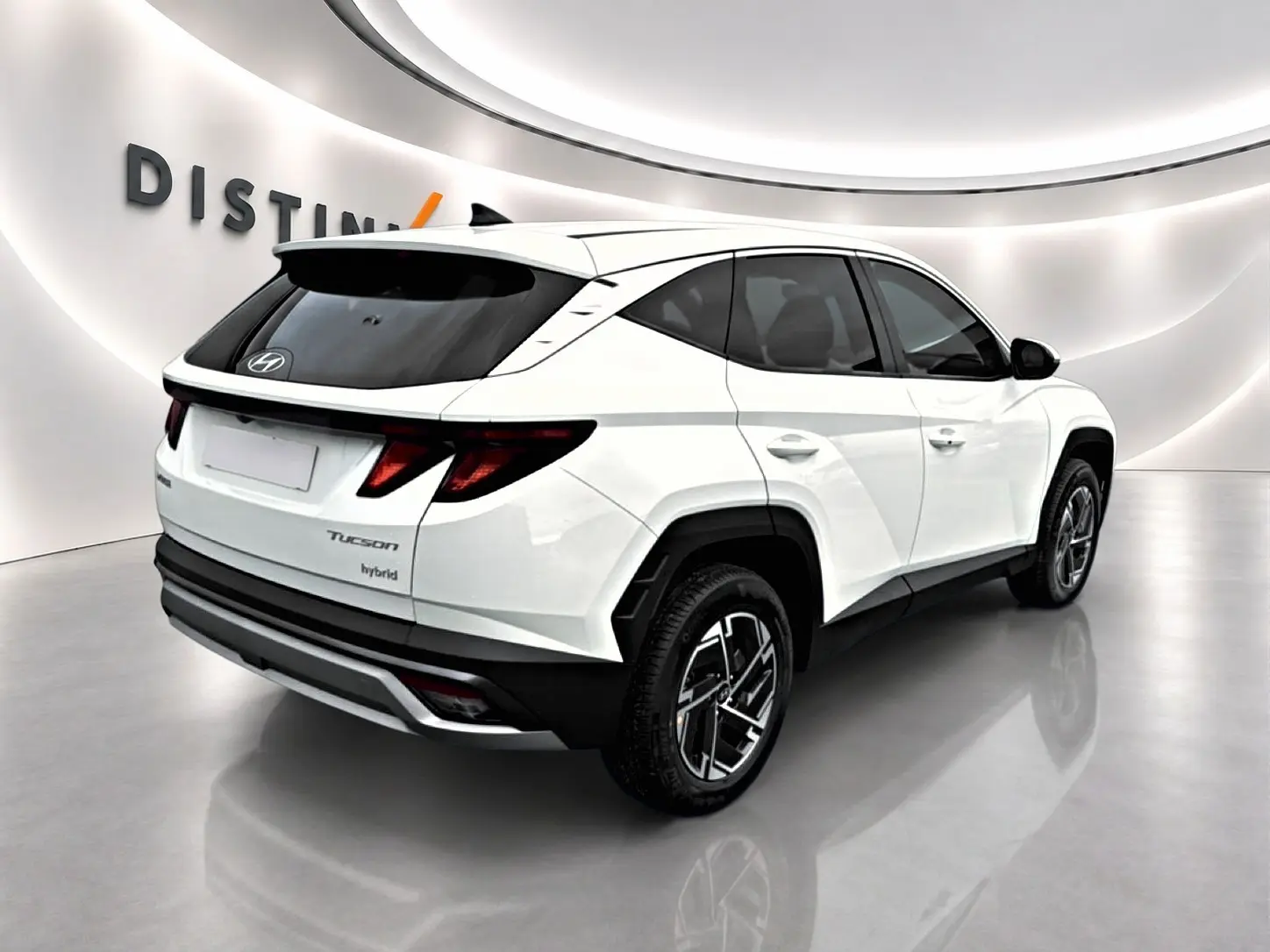 Vue 3/4 arrière droite d'un Hyundai Tucson blanc hybride avec jantes alliage et vitres teintées en showroom.