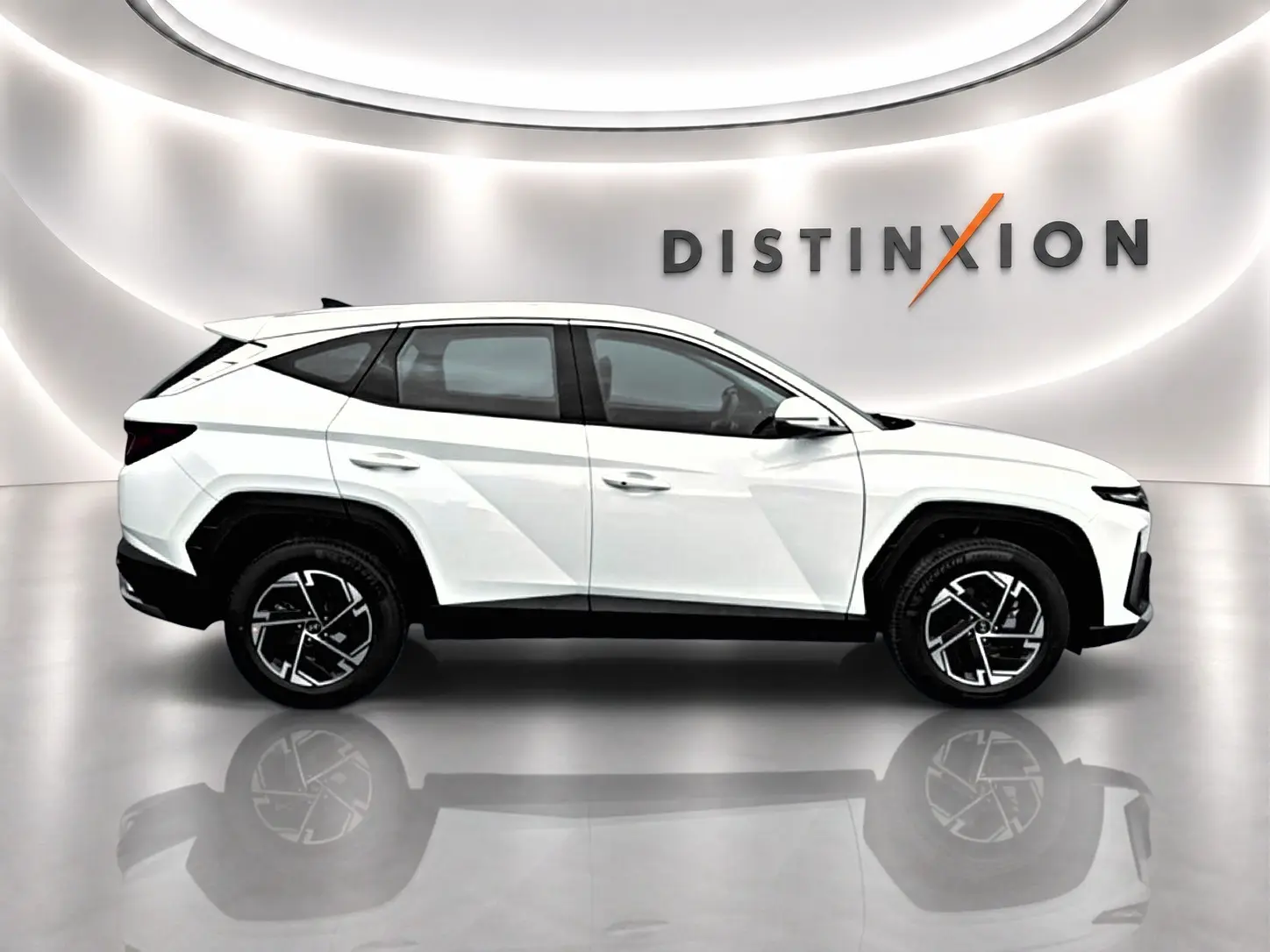 Vue de profil côté gauche du Hyundai Tucson blanc 2026 hybride avec jantes alliage et vitres teintées.