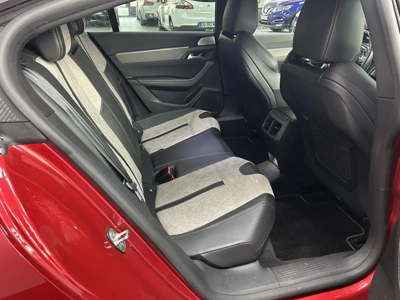 Vue côté gauche de l'habitacle arrière rouge clair d'une Peugeot 508 Hybrid avec sellerie bicolore cuir et alcantara.