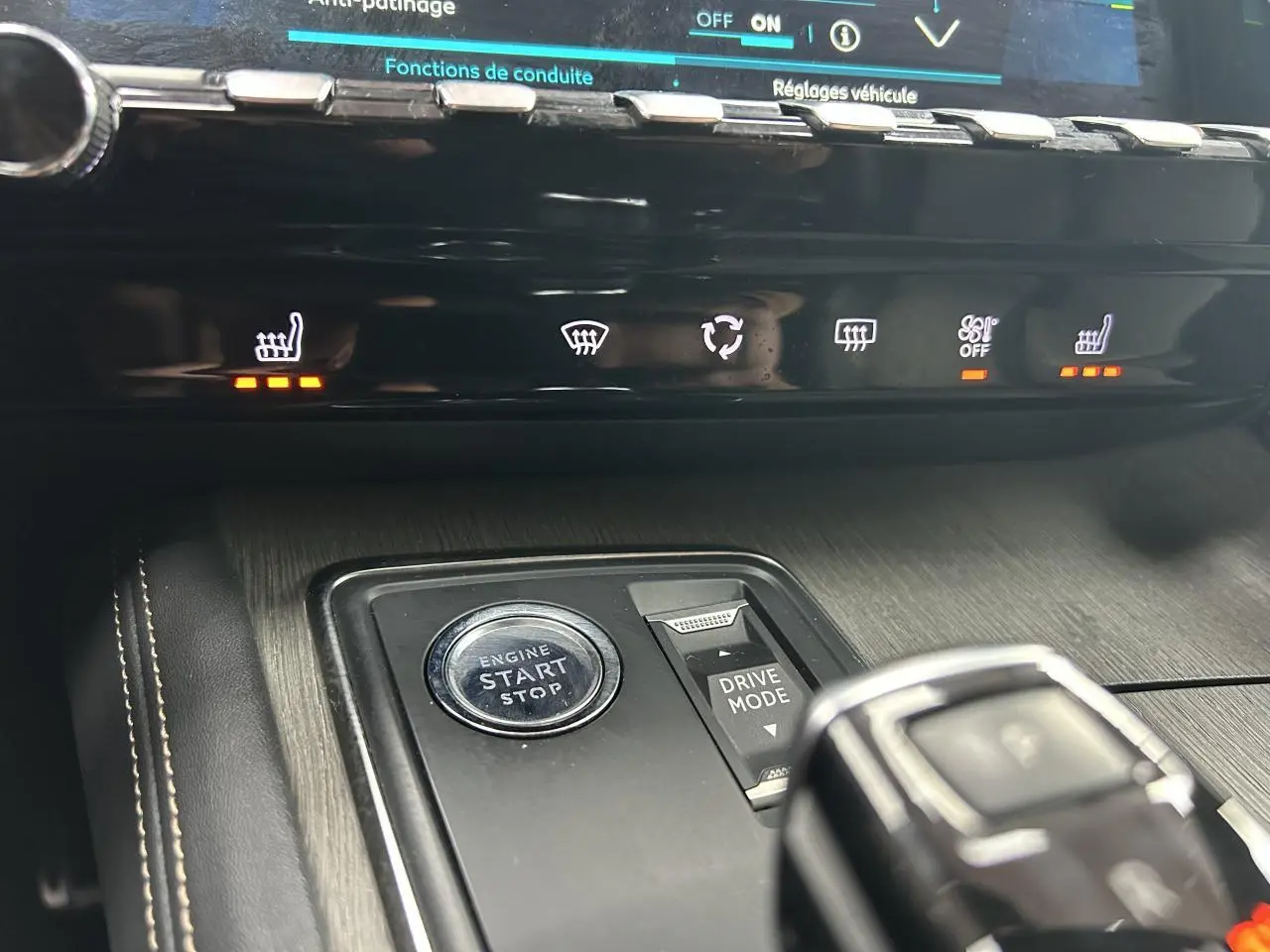 Gros plan sur la console centrale du Peugeot 508 Hybrid rouge clair, avec bouton start/stop et commandes chauffage activées.