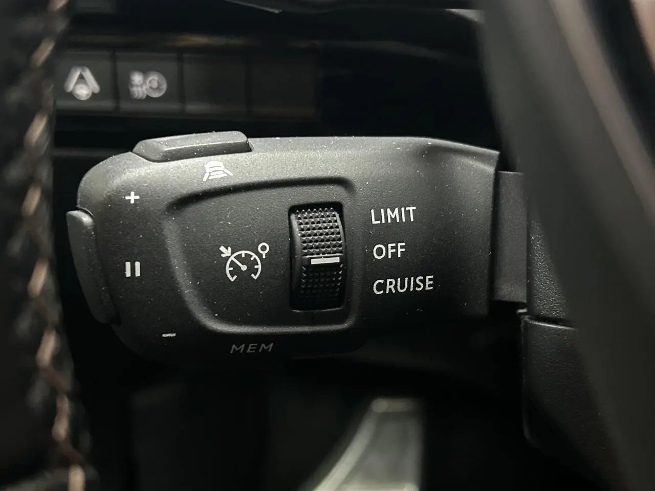 Gros plan sur la commande de régulateur de vitesse du Peugeot 508 Hybrid rouge clair, avec molette et pictogrammes blancs.