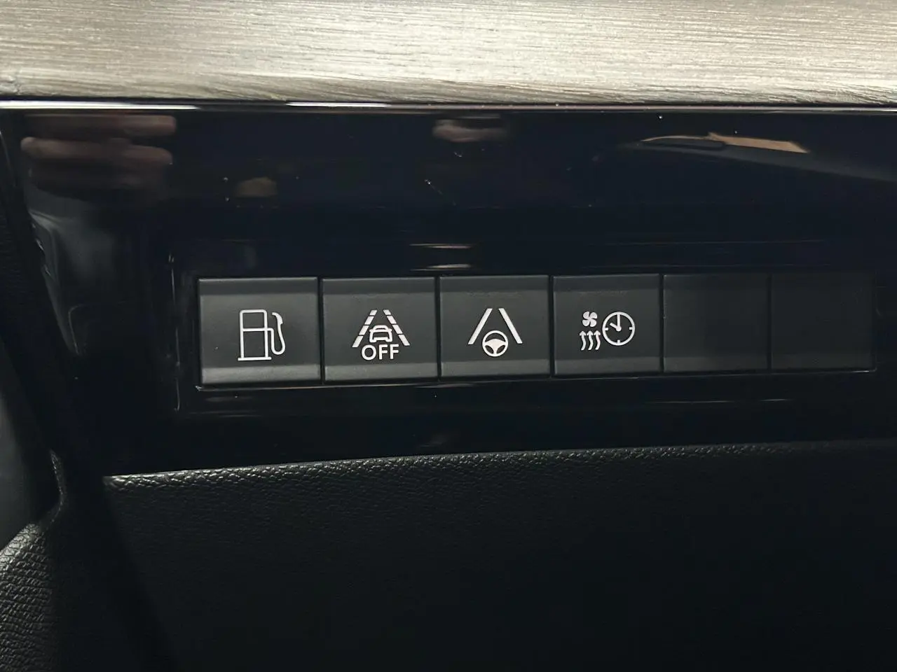 Boutons de commande du tableau de bord de la Peugeot 508 Hybrid rouge clair, avec aides à la conduite et chauffage.