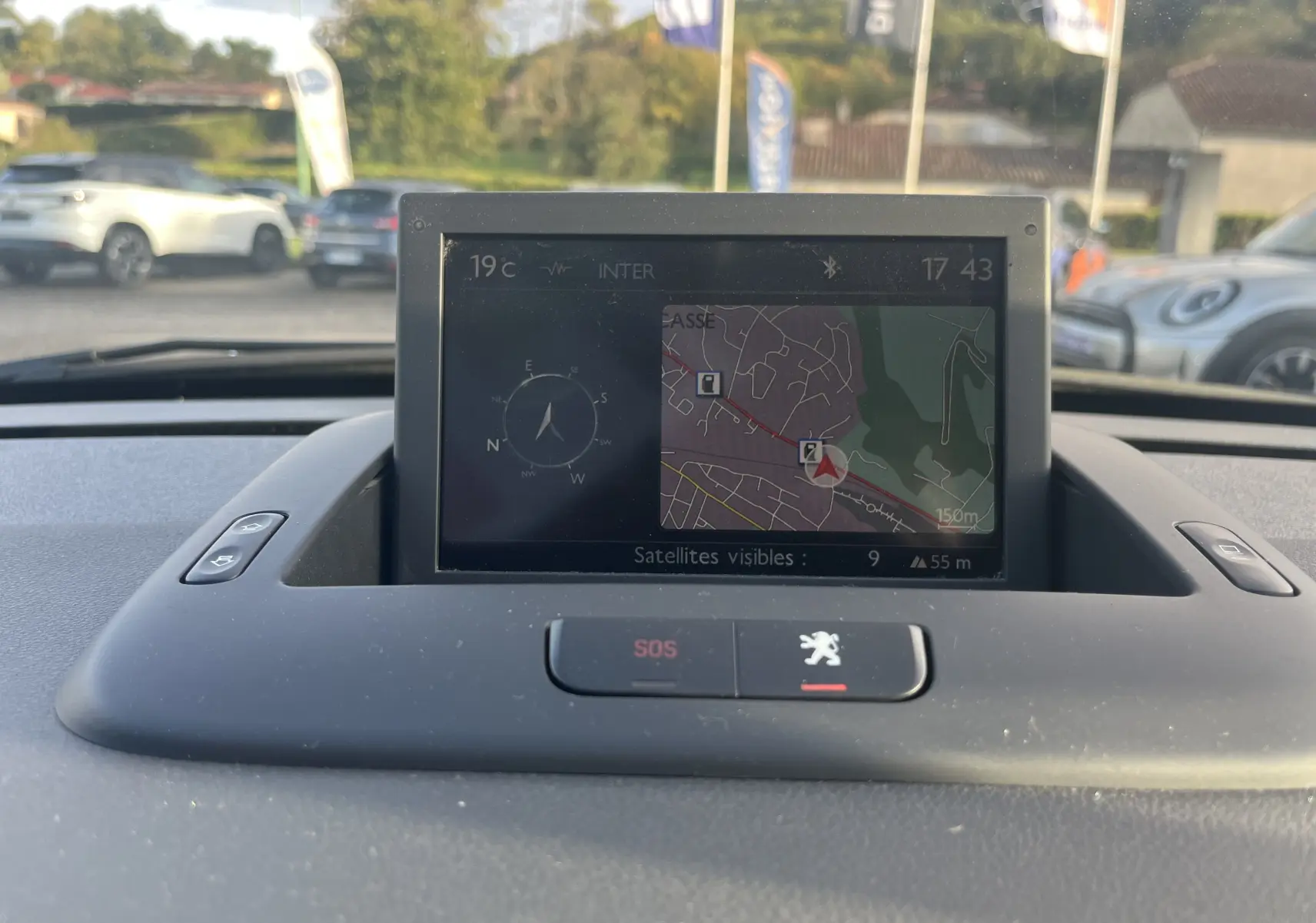 Écran GPS intégré au tableau de bord du Peugeot 5008 2013, avec vue extérieure floue en arrière-plan.