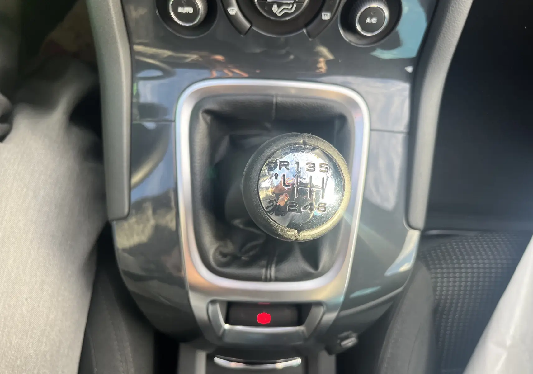 Gros plan sur le levier de vitesses manuel chromé du Peugeot 5008 2013 avec console noire brillante et bouton frein à main rouge.
