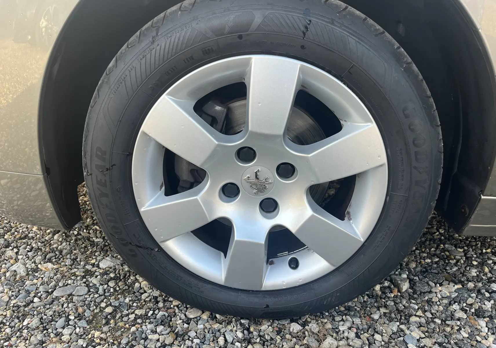 Gros plan sur la roue avant gauche d'une Peugeot 5008 2013, jante argentée avec pneu Goodyear visible.