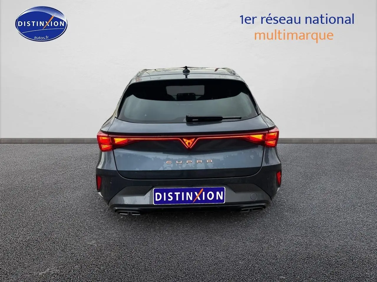 Vue arrière d'une CUPRA LEON ST gris magnétique avec feux LED allumés et double sortie d'échappement.