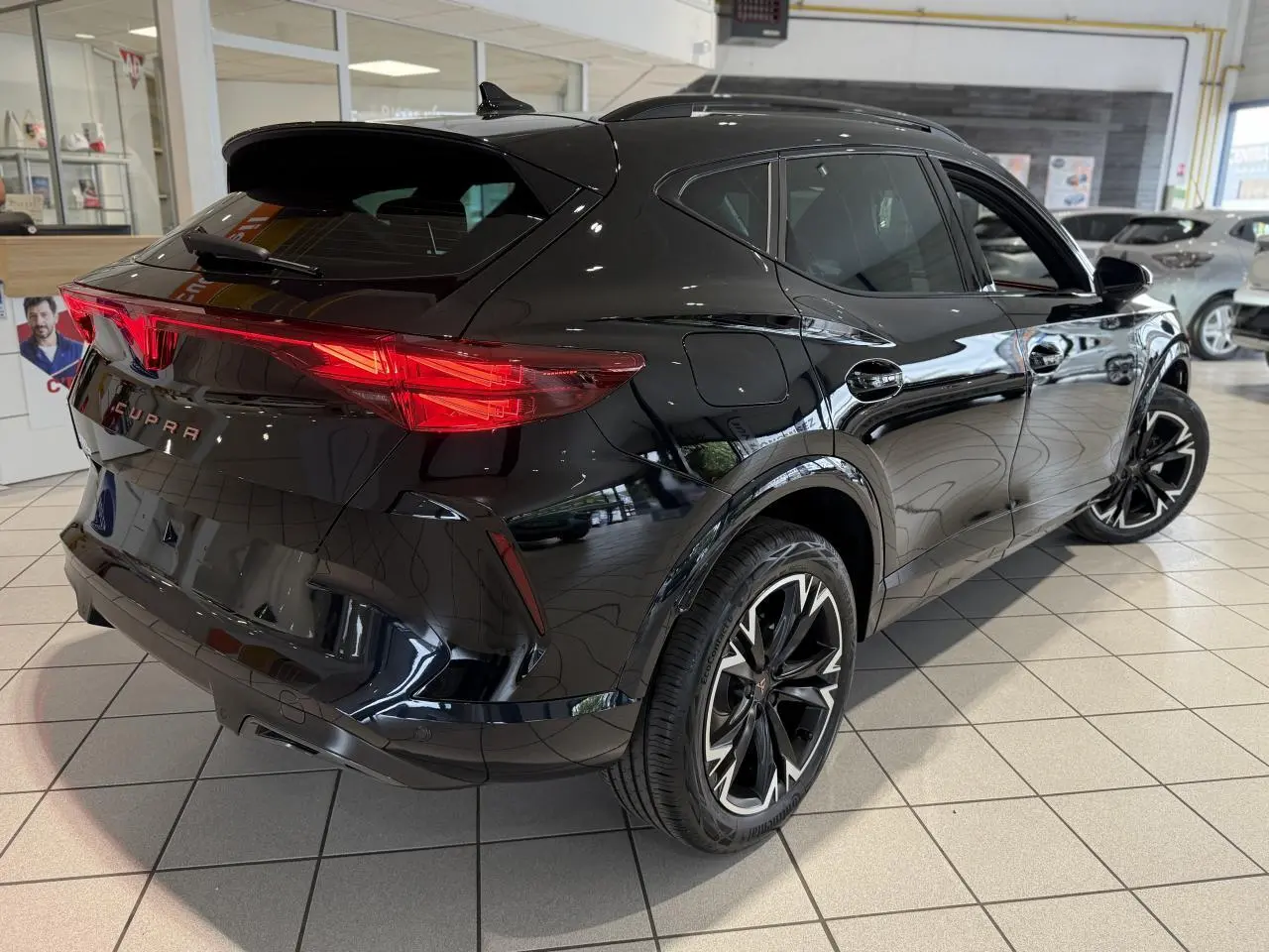 Vue 3/4 arrière droite du CUPRA Formentor noir Night avec feux arrière LED et jantes alliage 18 pouces en showroom.