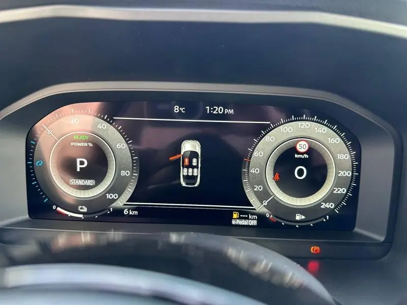 Tableau de bord numérique du Nissan Qashqai Hybrid e-POWER 2025, affichage des compteurs et état du véhicule en vue frontale.